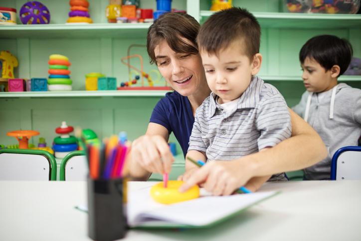 Enseignant aide le petit garçon en s'appuyant sur le livre