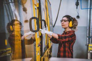 Apprenti-ingénieur féminin travaillant avec la machine CNC en usine