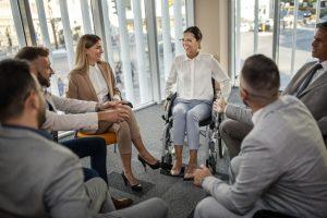 Femme d’affaires confiante en fauteuil roulant présentant lors d’une réunion d’affaires avec des collègues